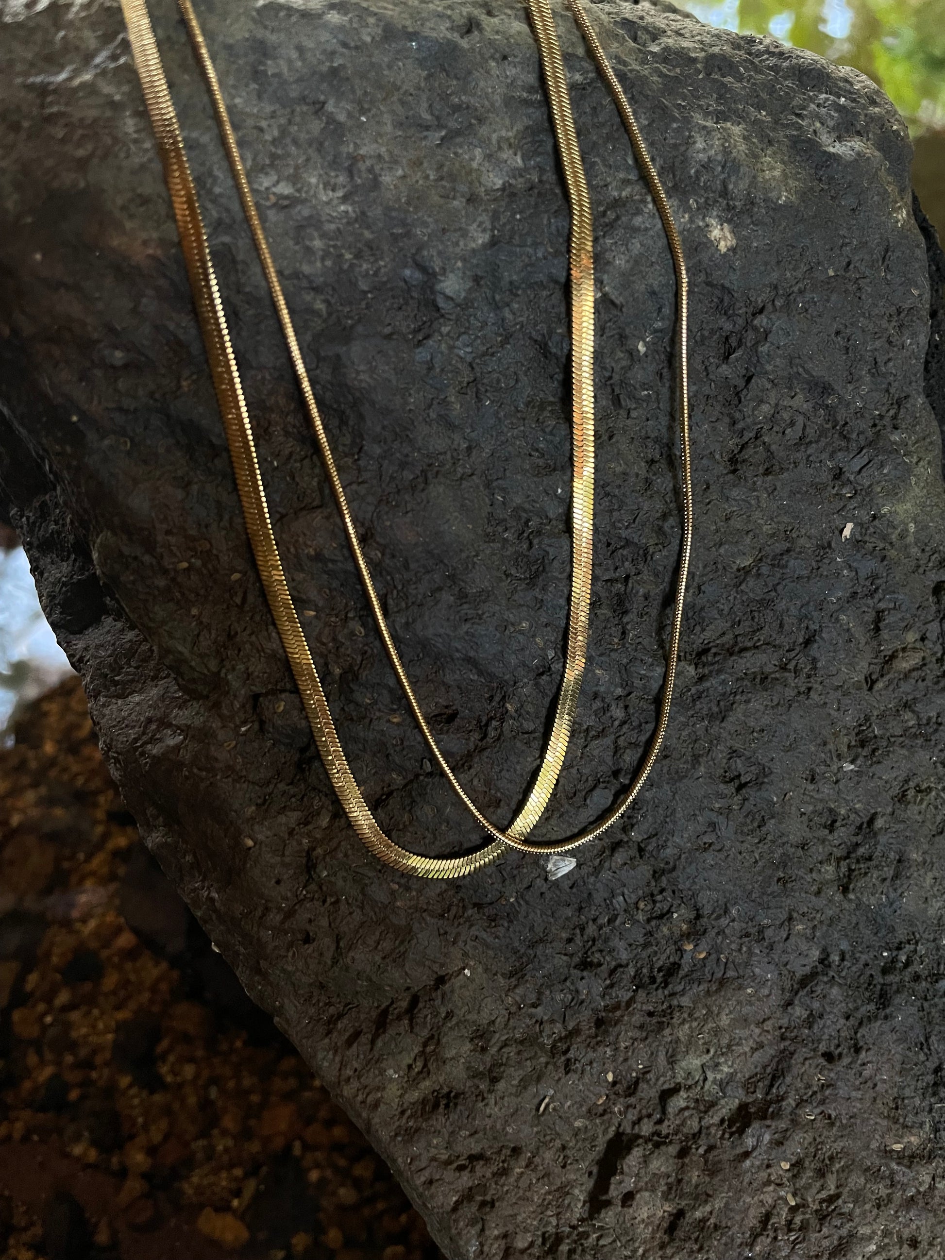 2 18k gold necklaces on a rock